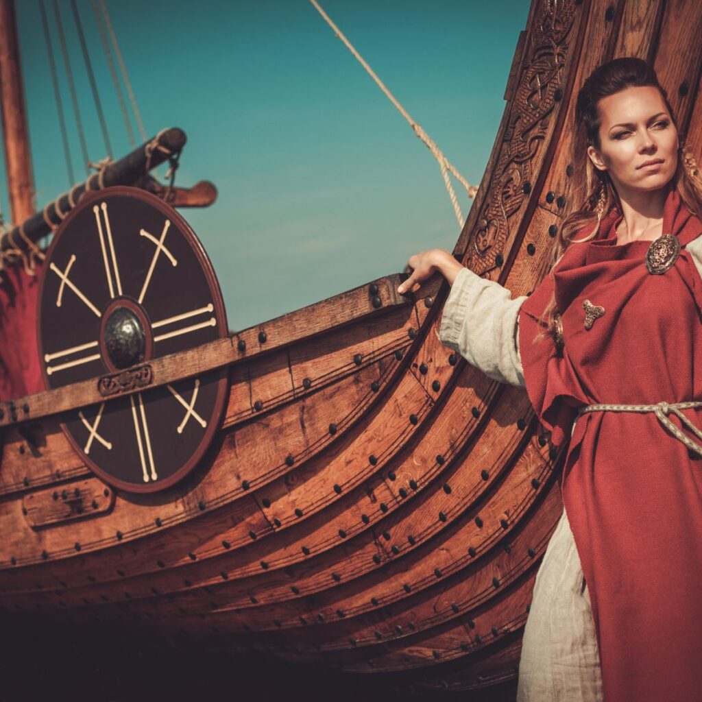 Viking woman in traditional clothes near drakkar